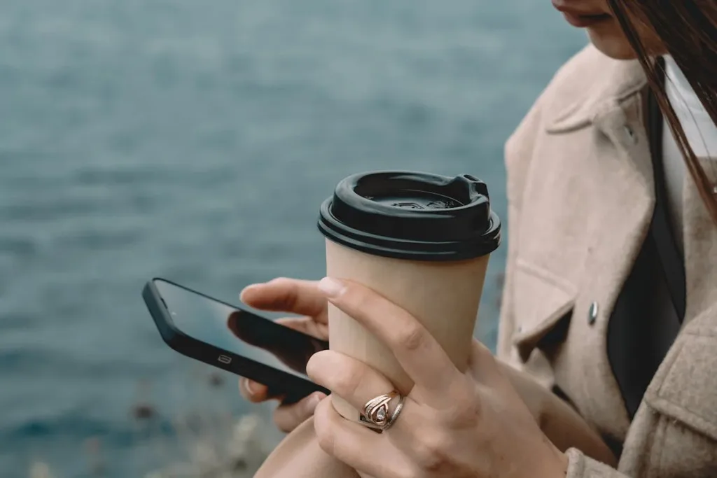 free close woman holding cup coffee and using